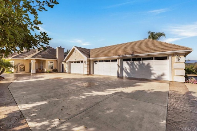 single story home featuring a tile roof, stucco siding, a chimney, a garage, and driveway