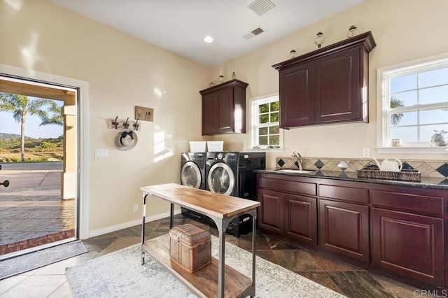 washroom with cabinet space, visible vents, washer and dryer, and a sink