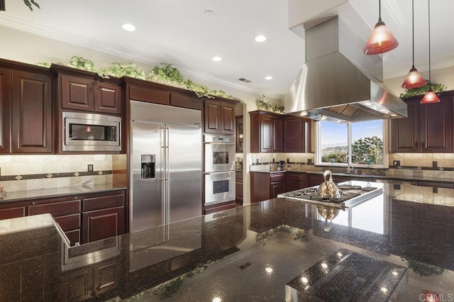 kitchen featuring island exhaust hood, ornamental molding, built in appliances, decorative light fixtures, and tasteful backsplash