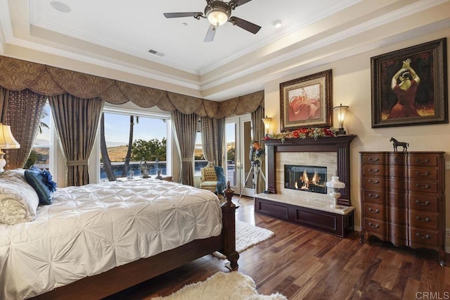 bedroom with visible vents, wood finished floors, a fireplace, a raised ceiling, and access to exterior