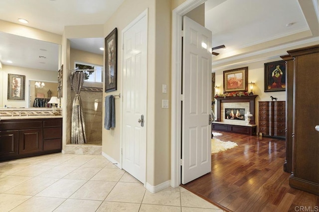 full bath featuring vanity, baseboards, a tile shower, a glass covered fireplace, and tile patterned floors