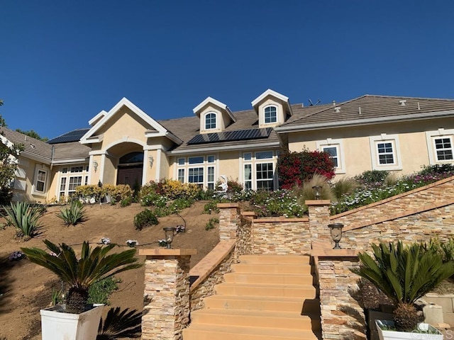 view of front of house featuring stucco siding and roof mounted solar panels