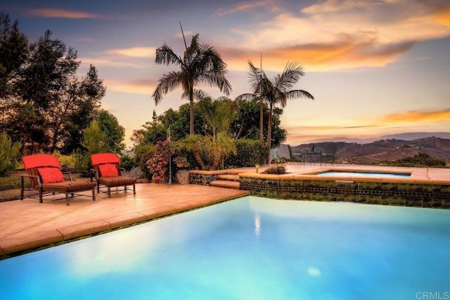 view of swimming pool with an in ground hot tub, a patio area, and a mountain view