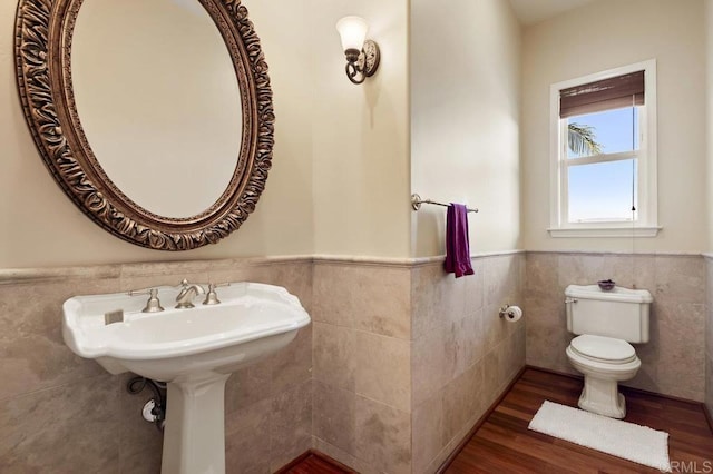 bathroom with a wainscoted wall, toilet, tile walls, and wood finished floors