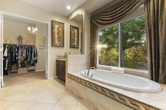 bathroom with a walk in closet, a garden tub, tile patterned flooring, a chandelier, and vanity