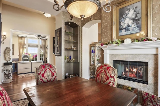 dining area with built in features, wood finished floors, a ceiling fan, and a premium fireplace