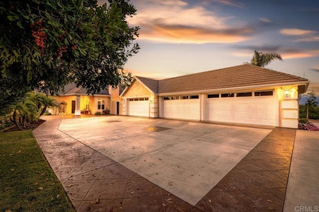 view of front of house with a tiled roof, stucco siding, driveway, and a garage