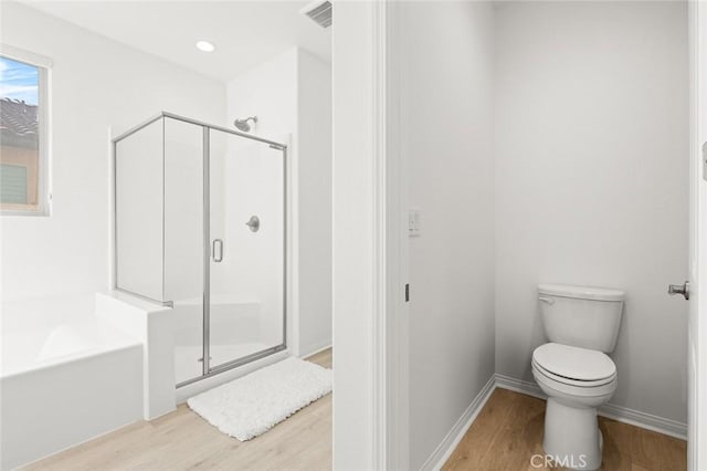 full bath featuring a stall shower, a bath, and wood finished floors