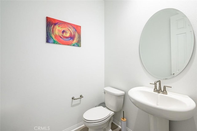 bathroom with a sink, toilet, and baseboards