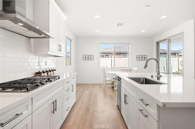 kitchen featuring a sink, visible vents, light countertops, appliances with stainless steel finishes, and wall chimney exhaust hood