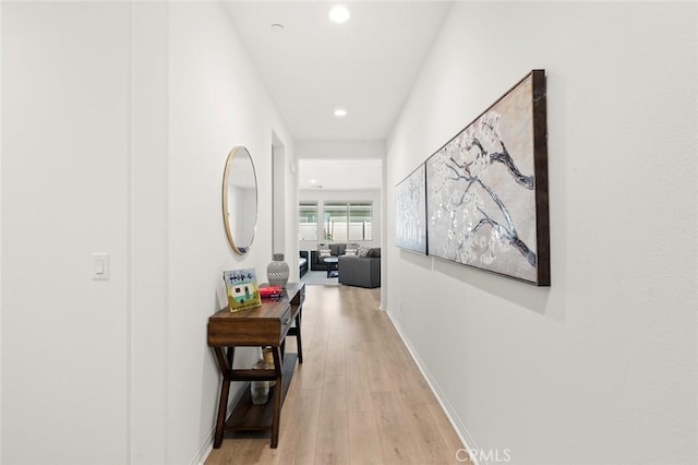 hall with light wood finished floors, baseboards, and recessed lighting