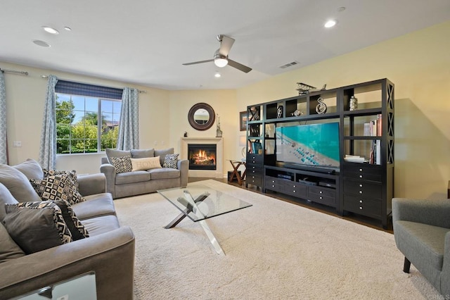 living area with ceiling fan, a lit fireplace, visible vents, and recessed lighting