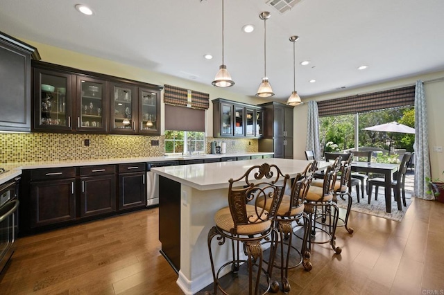 kitchen featuring a breakfast bar area, visible vents, a kitchen island, light countertops, and stainless steel dishwasher