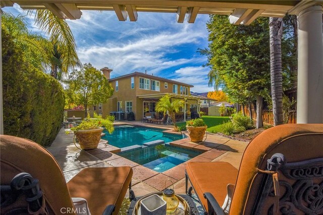 view of pool with fence, a pool with connected hot tub, and a patio area