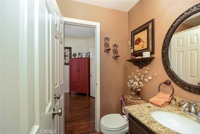 half bath featuring toilet, vanity, and wood finished floors