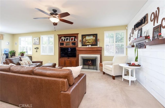 living room with a wealth of natural light, a fireplace with flush hearth, light carpet, and ceiling fan