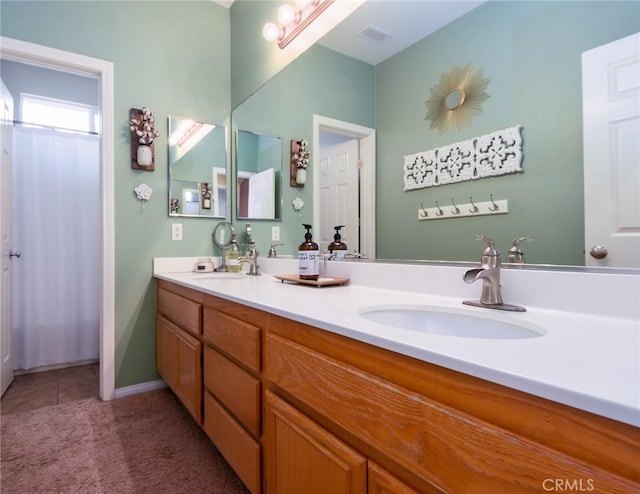 bathroom with a sink, visible vents, double vanity, and tile patterned floors