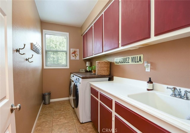 laundry room featuring light tile patterned floors, baseboards, cabinet space, a sink, and washing machine and dryer