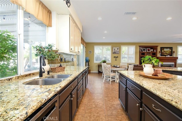 kitchen with visible vents, a sink, light stone counters, stainless steel dishwasher, and light tile patterned floors