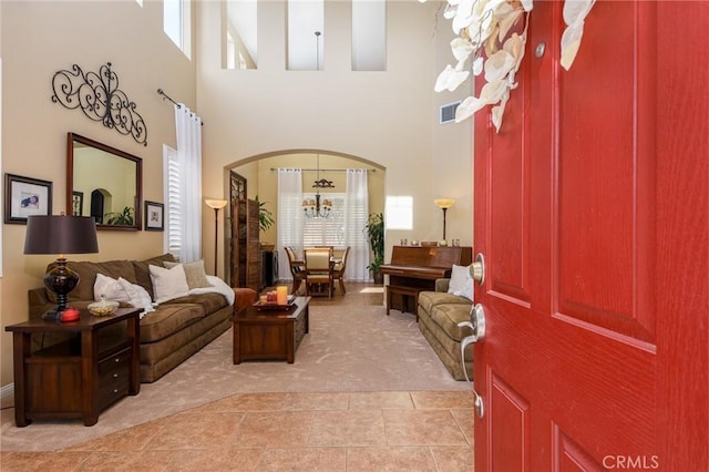 foyer entrance featuring arched walkways, light tile patterned floors, light colored carpet, and visible vents