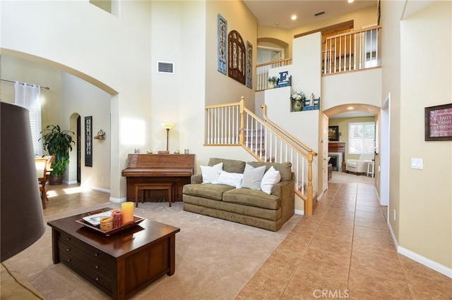 living room with arched walkways, visible vents, a fireplace, and stairs