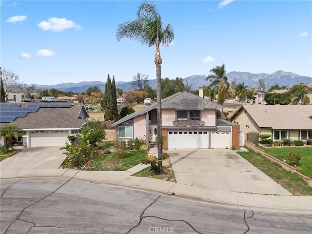 view of front of property with a garage, a shingled roof, concrete driveway, a mountain view, and a front lawn