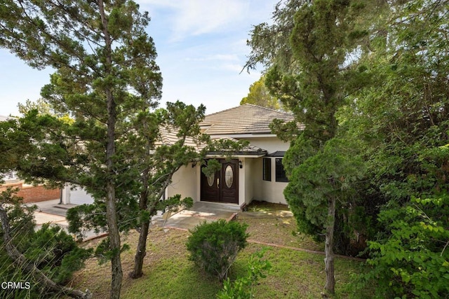 view of front of home featuring a tiled roof, an attached garage, and stucco siding