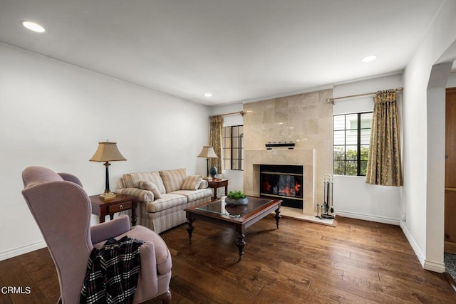 living area with hardwood / wood-style floors, a tiled fireplace, recessed lighting, and baseboards