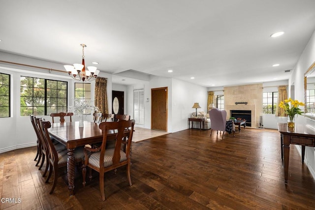 dining room featuring a notable chandelier, a fireplace, recessed lighting, wood-type flooring, and baseboards