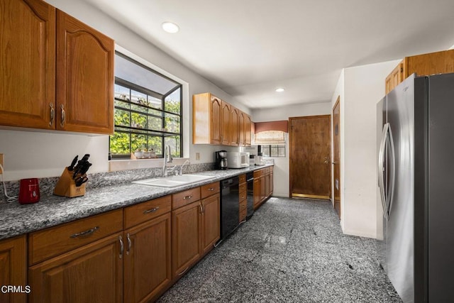 kitchen featuring dishwasher, brown cabinets, a sink, and freestanding refrigerator