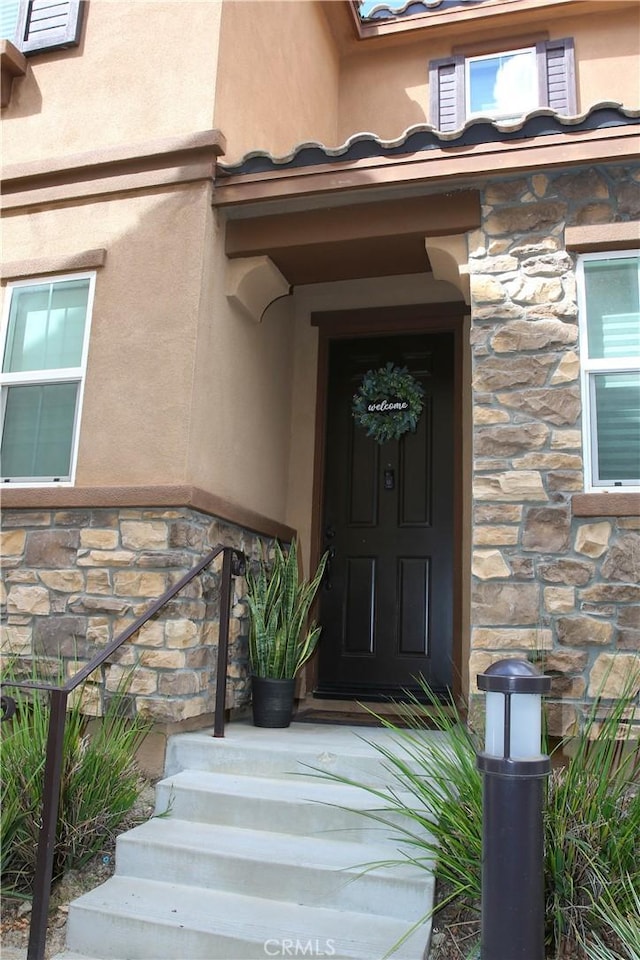 property entrance with stone siding and stucco siding