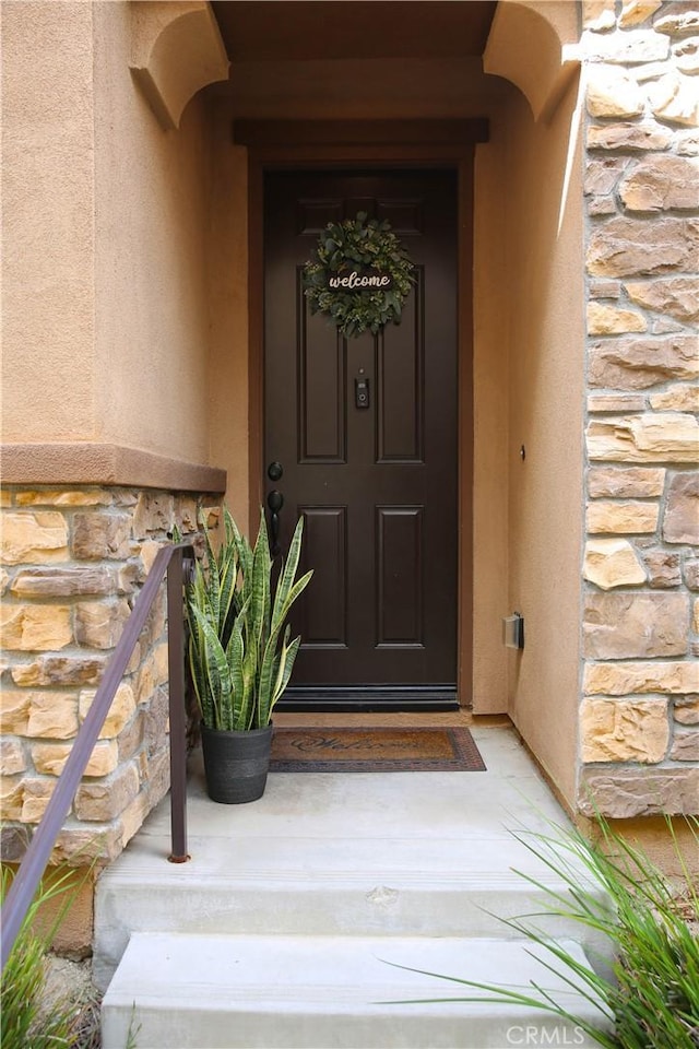 property entrance with stone siding and stucco siding