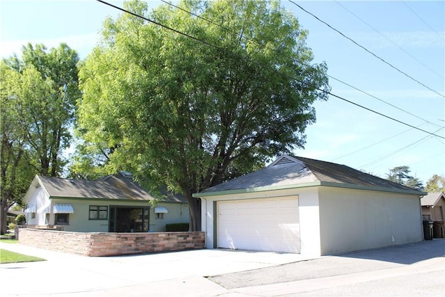 view of front facade featuring a garage, an outdoor structure, and stucco siding