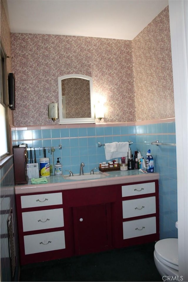 bar with a wainscoted wall, a sink, tile walls, and wallpapered walls