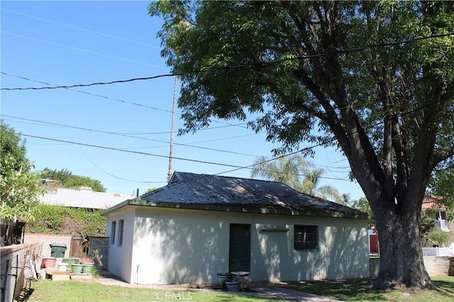 back of house with a yard, fence, and stucco siding