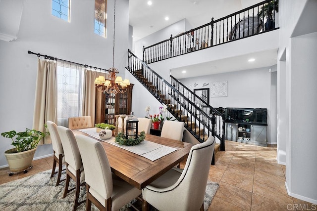 tiled dining room with a towering ceiling, a notable chandelier, stairway, and baseboards