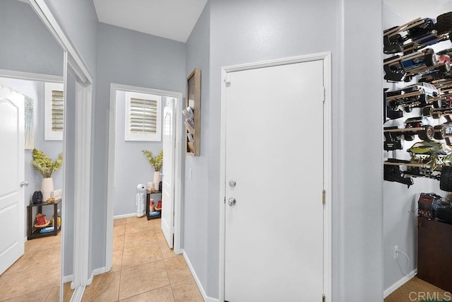 corridor featuring light tile patterned floors and baseboards