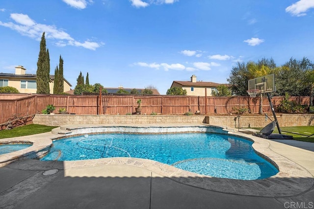 view of pool featuring a fenced backyard, a pool with connected hot tub, and a patio