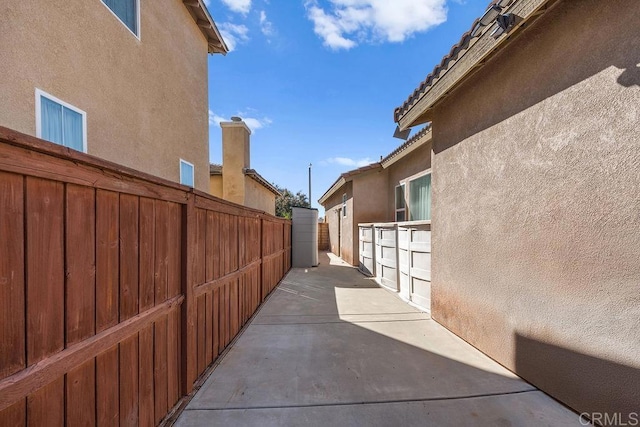 view of side of home featuring fence, a patio, and stucco siding