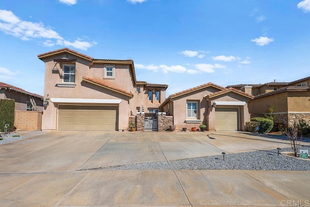 mediterranean / spanish house with concrete driveway, a tile roof, a gate, fence, and stucco siding