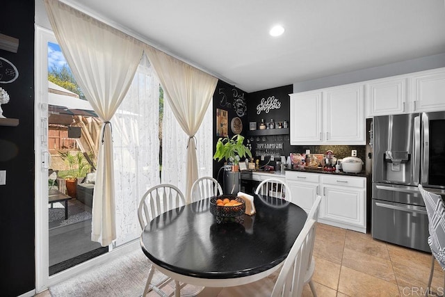 interior space featuring light tile patterned floors, dark countertops, white cabinetry, and stainless steel fridge with ice dispenser