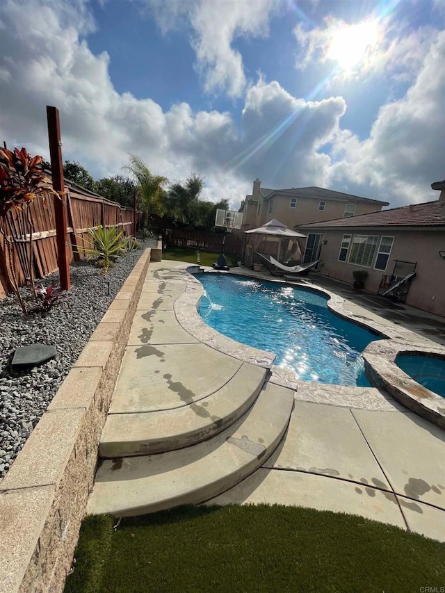 view of swimming pool with a patio area, a fenced backyard, a fenced in pool, and an in ground hot tub