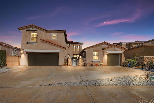 mediterranean / spanish house featuring a tiled roof, fence, a gate, and stucco siding