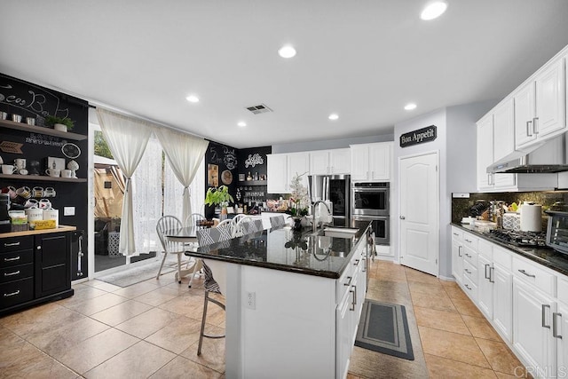 kitchen with stainless steel appliances, visible vents, white cabinets, under cabinet range hood, and a kitchen bar