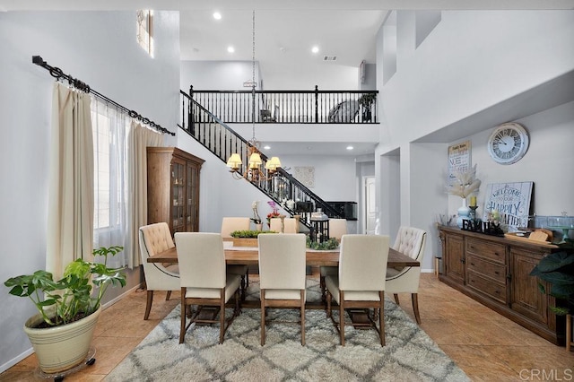 tiled dining area featuring visible vents, baseboards, a towering ceiling, stairs, and a notable chandelier