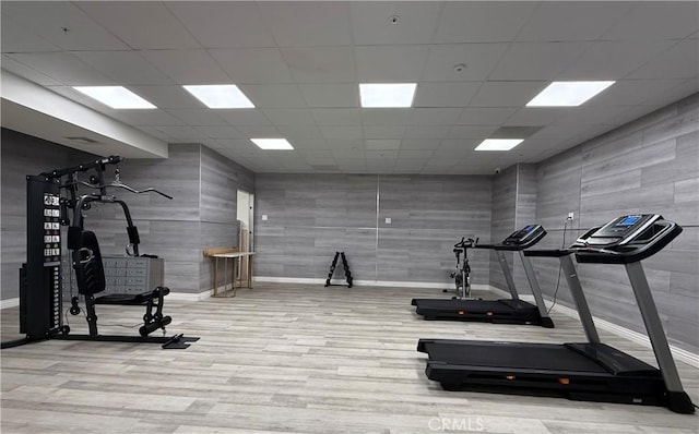 workout area with a paneled ceiling, baseboards, and wood finished floors