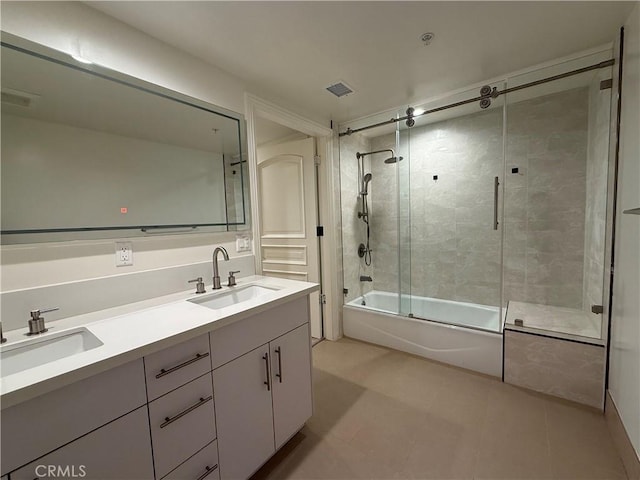 bathroom with double vanity, visible vents, bath / shower combo with glass door, and a sink