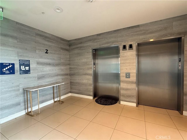 kitchen featuring elevator, light tile patterned floors, and baseboards