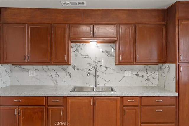 812 Toomes Ave, Corning, CA 96021 - kitchen with brown cabinets, a sink, visible vents, light stone countertops, and decorative backsplash