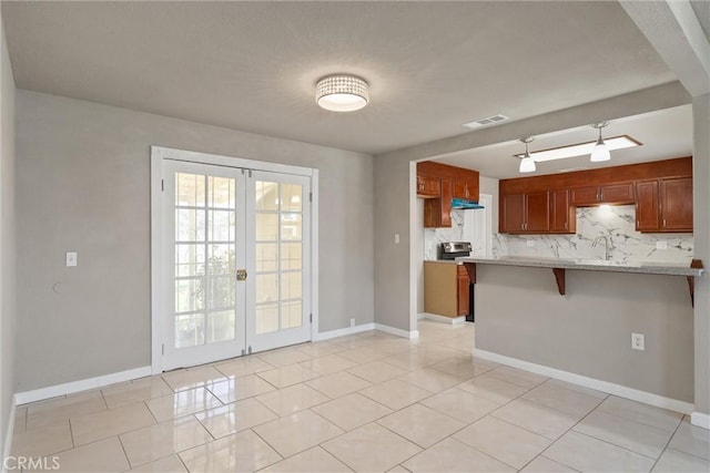 812 Toomes Ave, Corning, CA 96021 - kitchen featuring a peninsula, brown cabinetry, french doors, and a breakfast bar